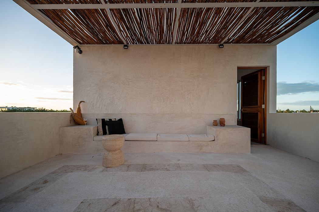 Rustic outdoor patio with thatched roof, textured walls, and minimalist furnishings.