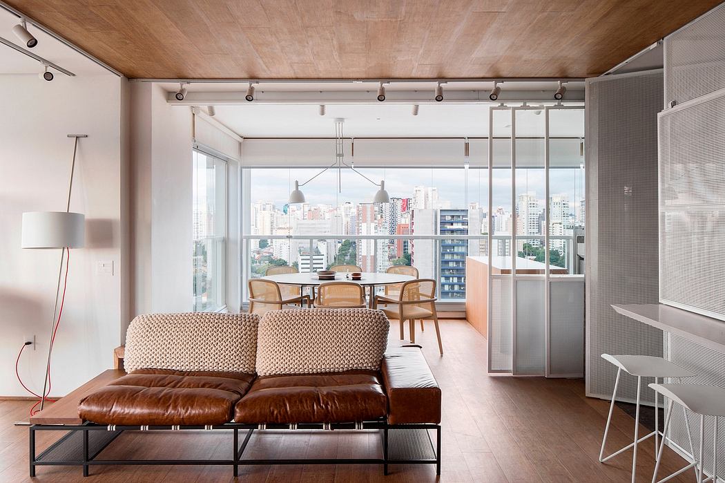 A modern, open-concept living space with a view of the city skyline. Warm wood tones, industrial lighting, and leather furnishings create a stylish ambiance.
