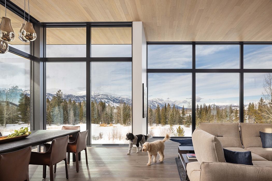 Modern, open-concept living area with large windows showcasing snowy mountain landscape.