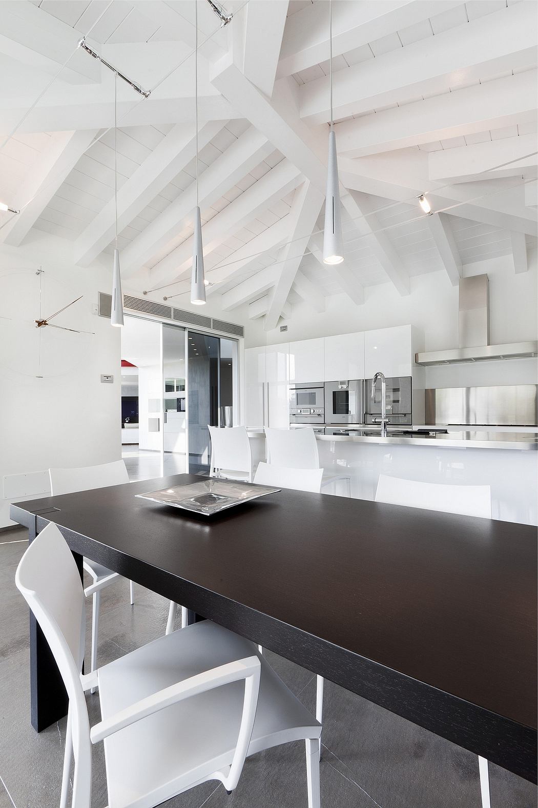Striking modern kitchen with angular white ceiling, sleek dark countertops, and minimalist lighting.