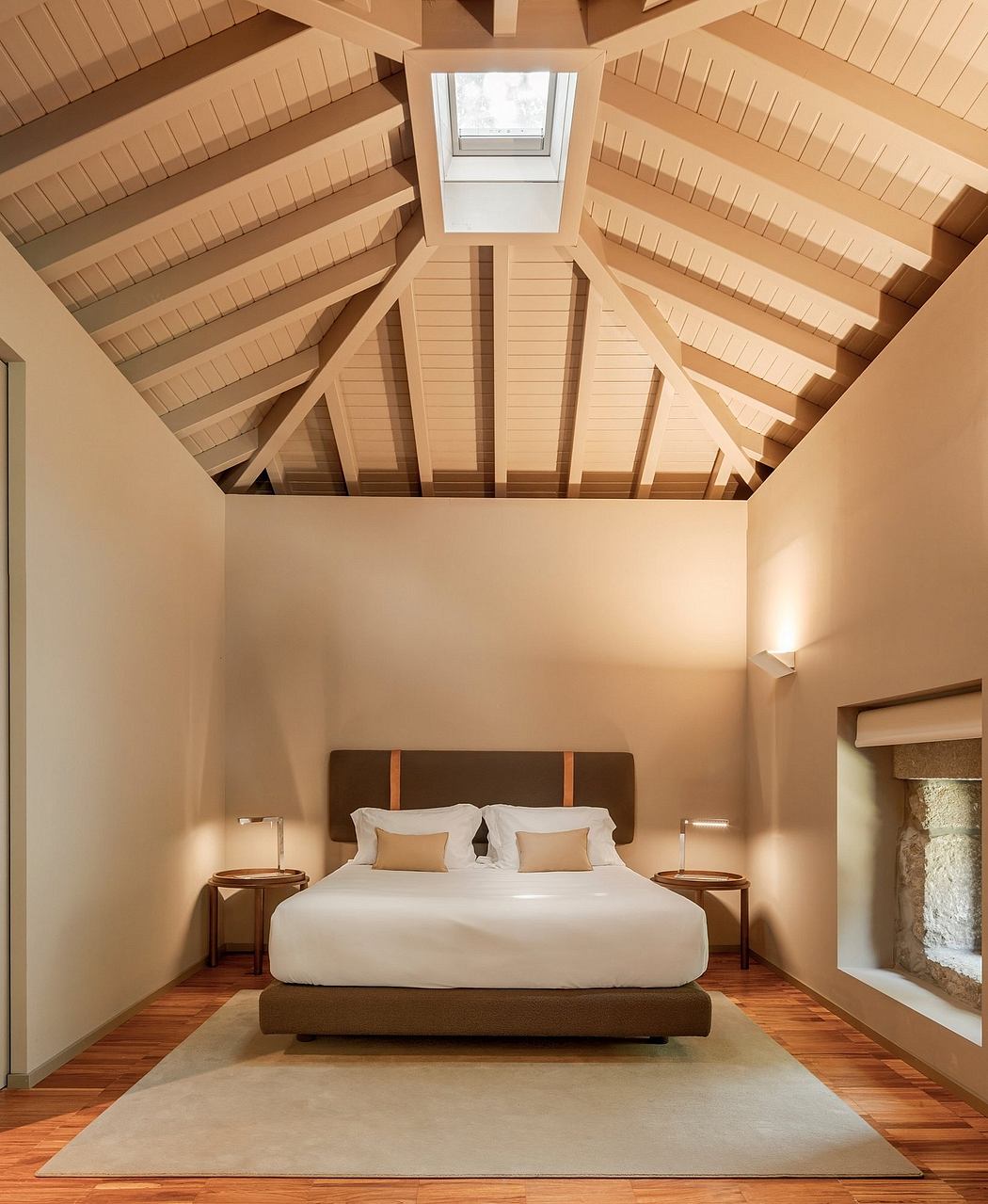 Warm, inviting bedroom interior with a vaulted wooden ceiling and minimalist furnishings.
