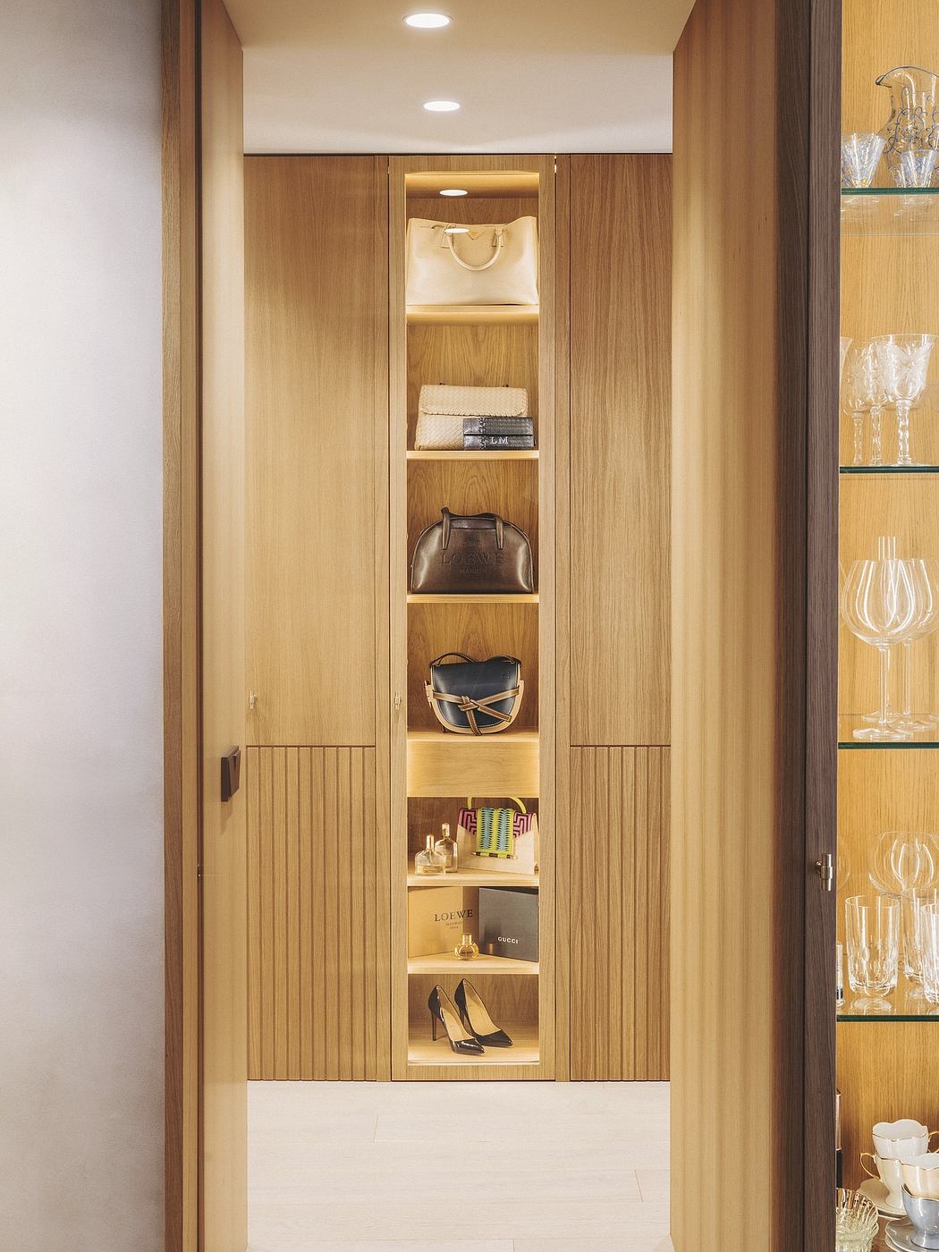 Minimalist wooden cabinetry with recessed lighting and display shelves.