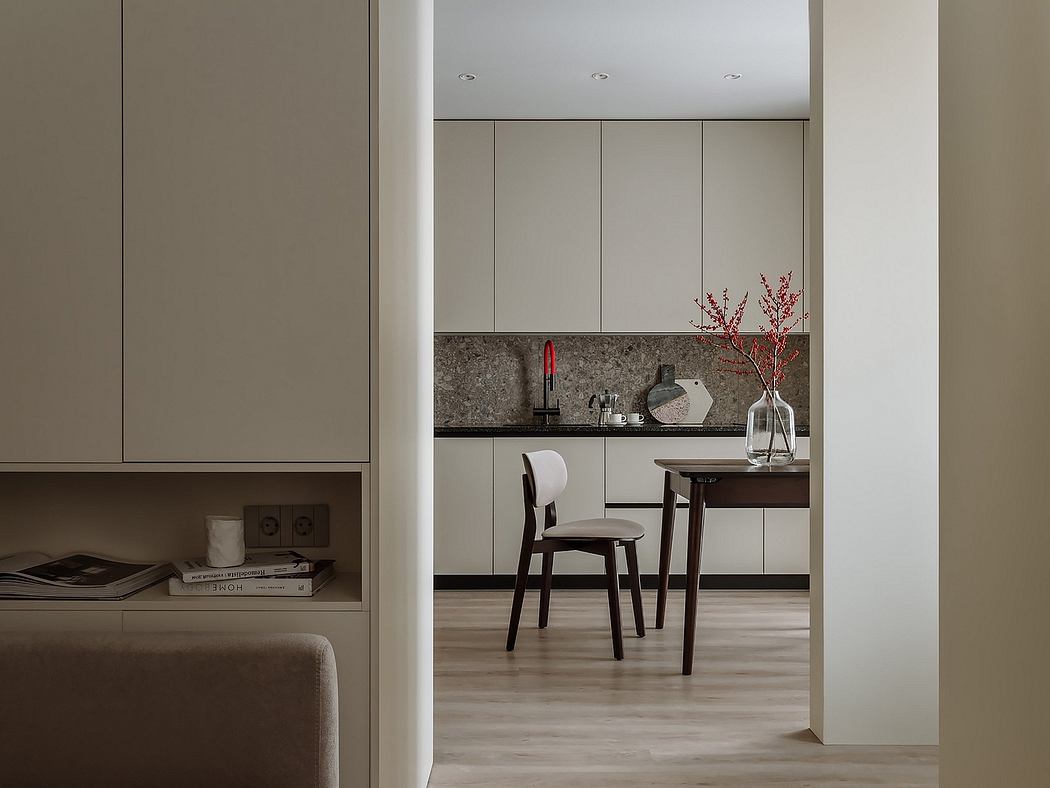 A modern, minimalist kitchen with sleek cabinets, a granite countertop, and a wooden dining table.