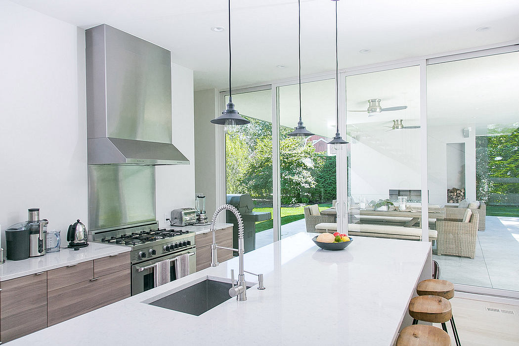 Sleek kitchen with stainless steel appliances, glass walls, and modern lighting fixtures.