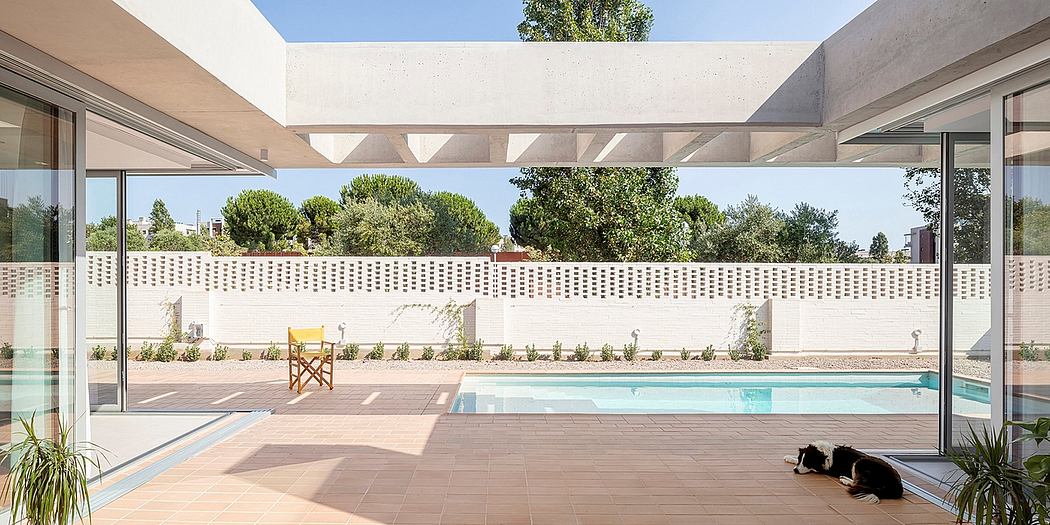 Glass-walled courtyard with concrete structure, pool, and landscaping.