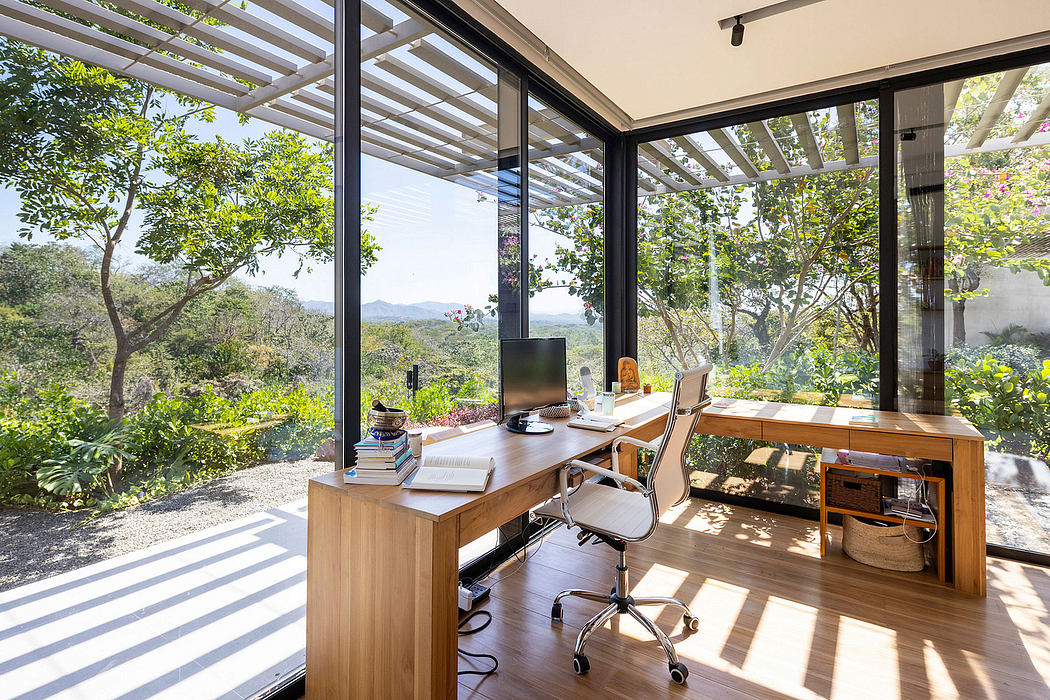 Spacious home office with glass walls overlooking lush greenery and mountain views.