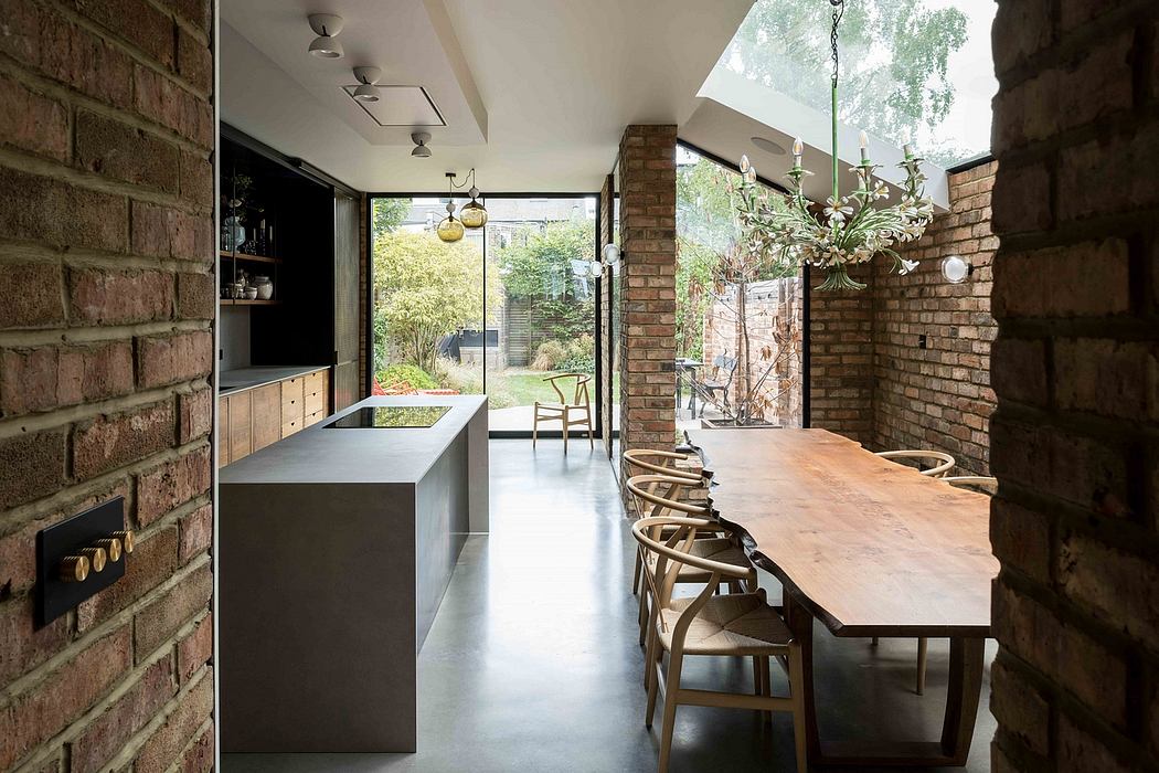 Brick walls, natural light, long dining table, and industrial-style lighting characterize this modern interior.