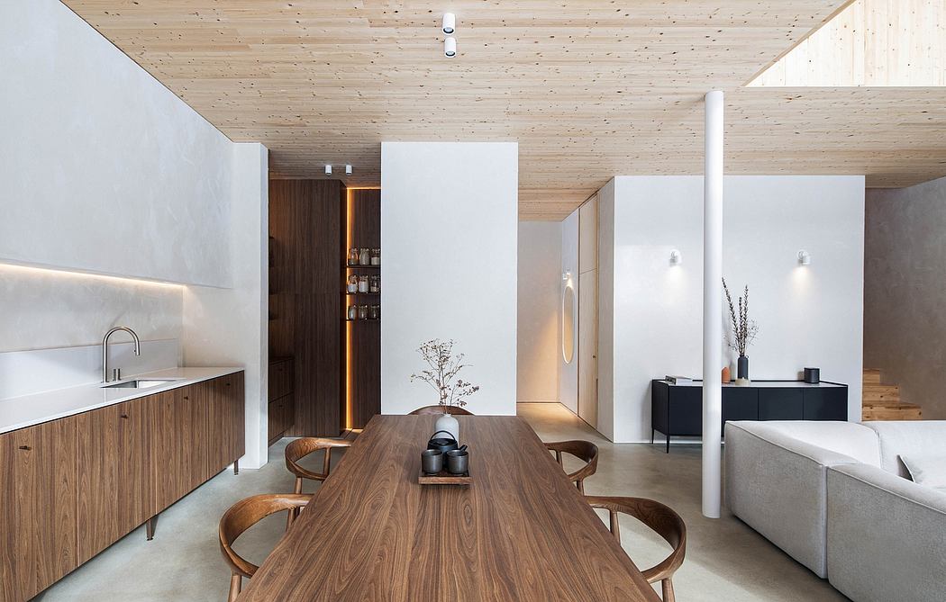 Minimalist, wood-paneled interior with sleek kitchen, dining table, and modern furnishings.