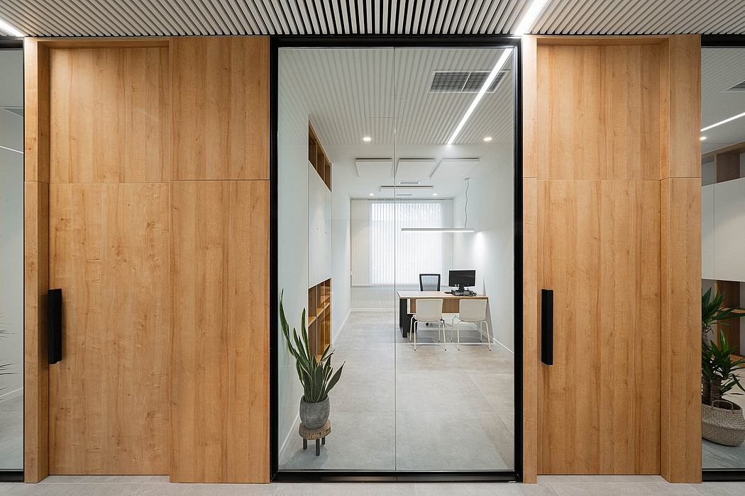 Minimalist office space with wood paneling, glass doors, and modern furnishings.