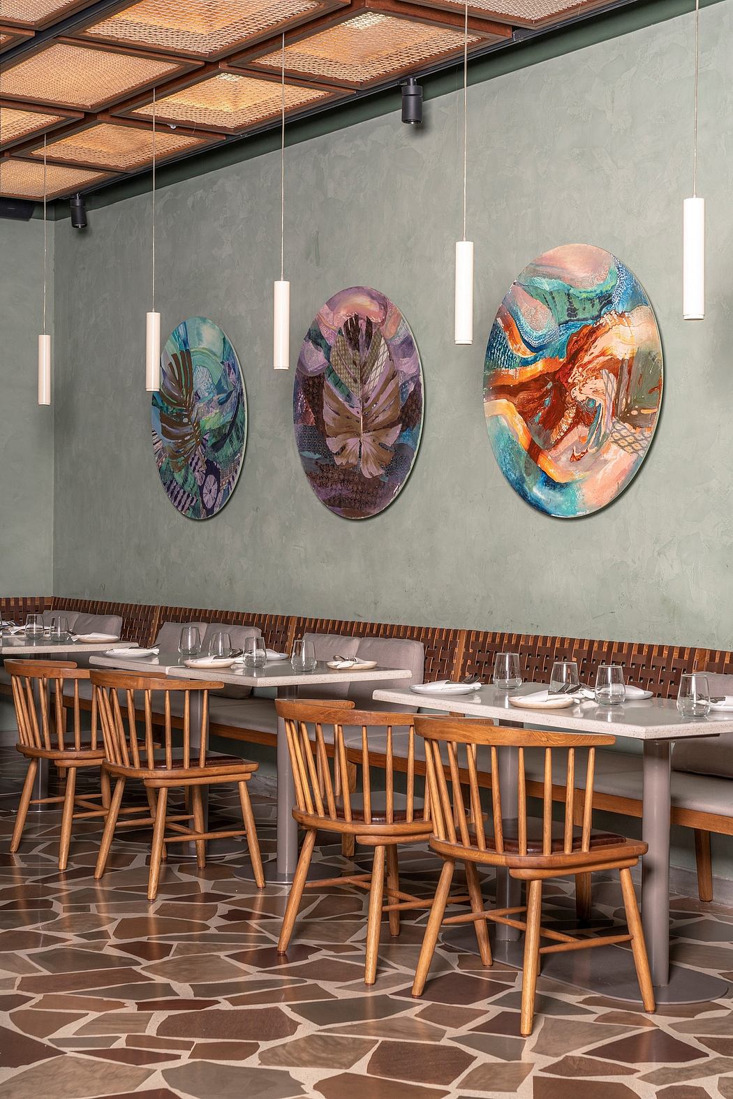 Cozy restaurant with vibrant abstract artwork, wooden furniture, and patterned flooring.