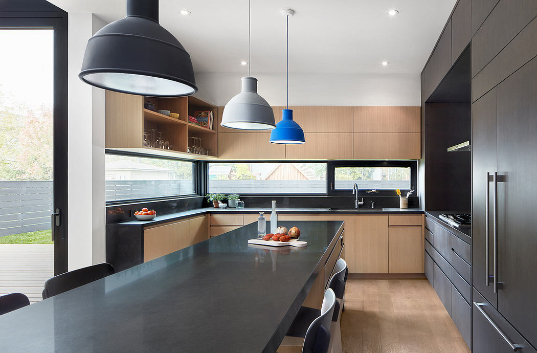 Sleek modern kitchen with wood cabinetry, black countertops, and pendant lights.