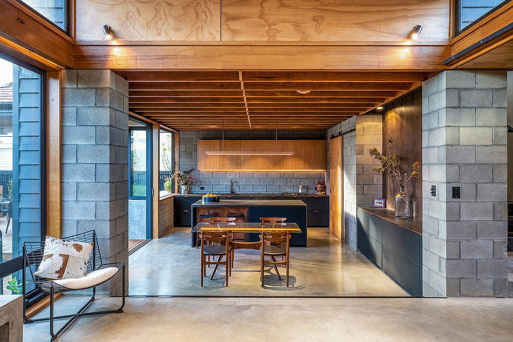 Rustic wood-paneled ceiling, concrete walls, and modern kitchen and dining setup.