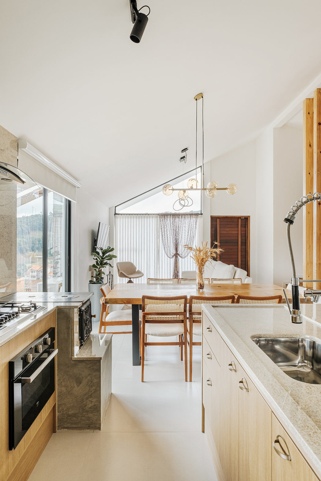 Sleek, contemporary kitchen with wooden cabinetry, pendant lighting, and a dining area with wood table and chairs.