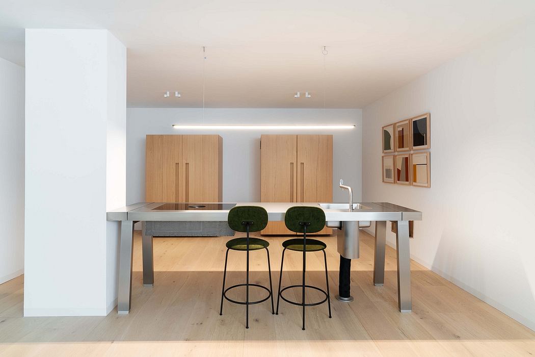 Clean, minimalist kitchen with sleek stainless steel countertops, wooden cabinetry, and stylish bar stools.