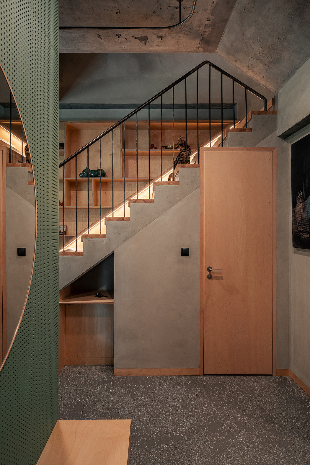A modern, minimalist interior design with concrete walls, wooden stairs, and a sleek door.