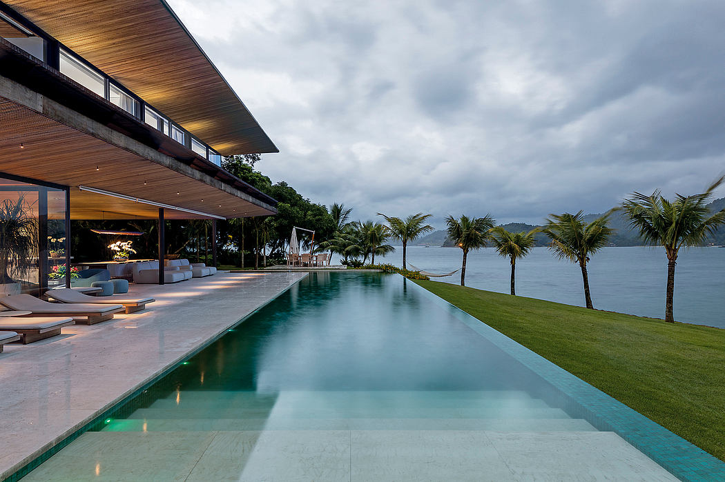 A modern, open-concept villa with a large infinity pool overlooking a tropical beach.