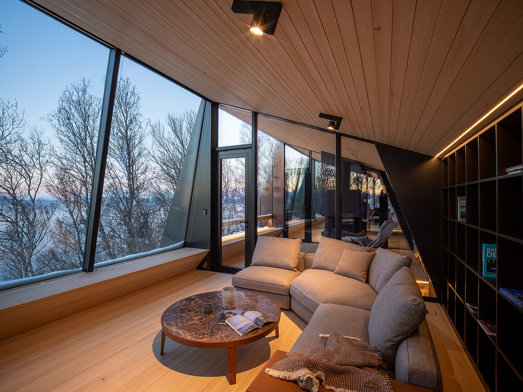 Cozy living space with expansive windows overlooking scenic nature view and wood-paneled ceiling.