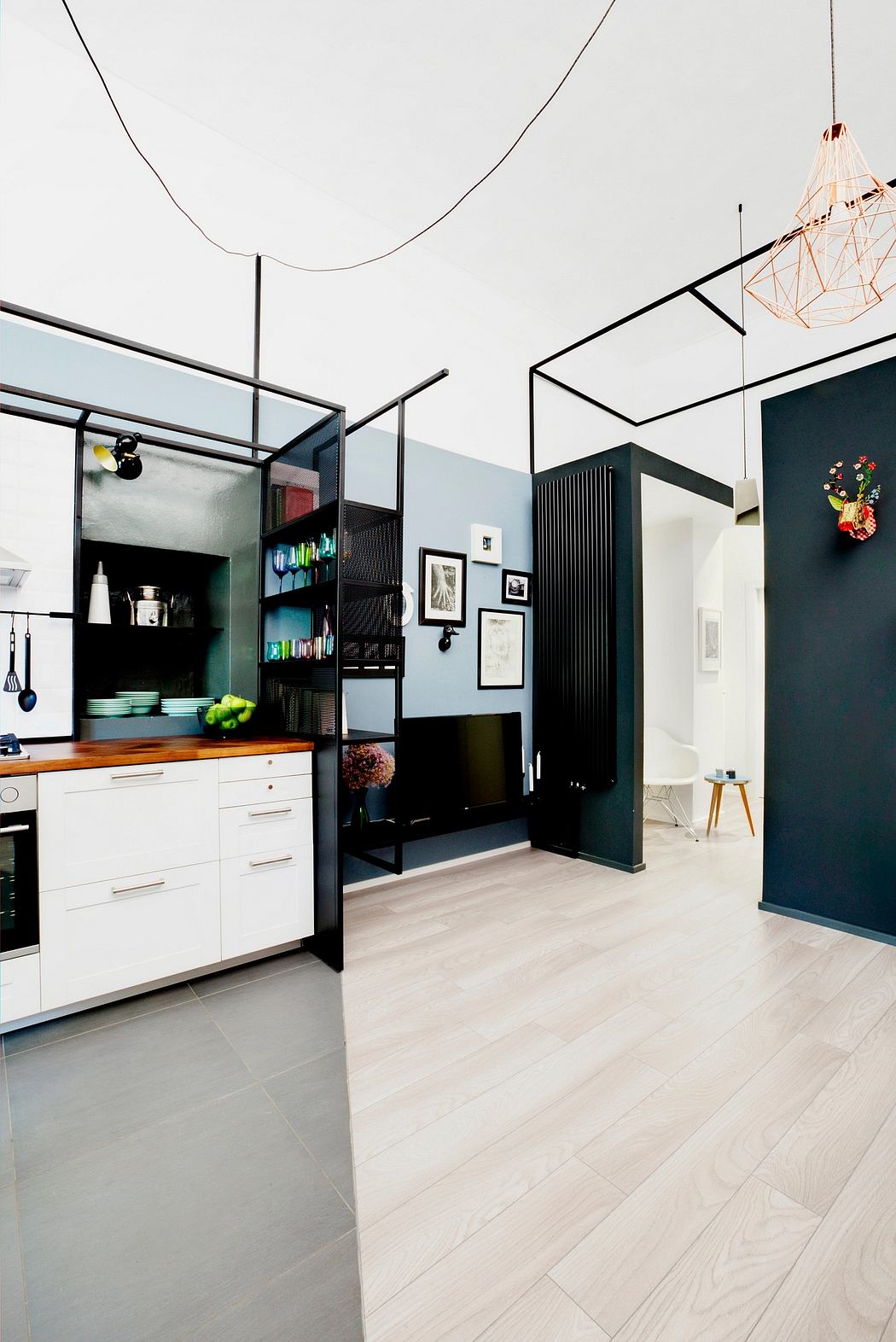 Modern kitchen layout with black and white color scheme, geometric lighting fixtures, and open shelving.
