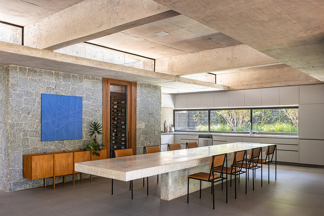 Spacious modern kitchen with stone walls, large concrete dining table, and artwork.