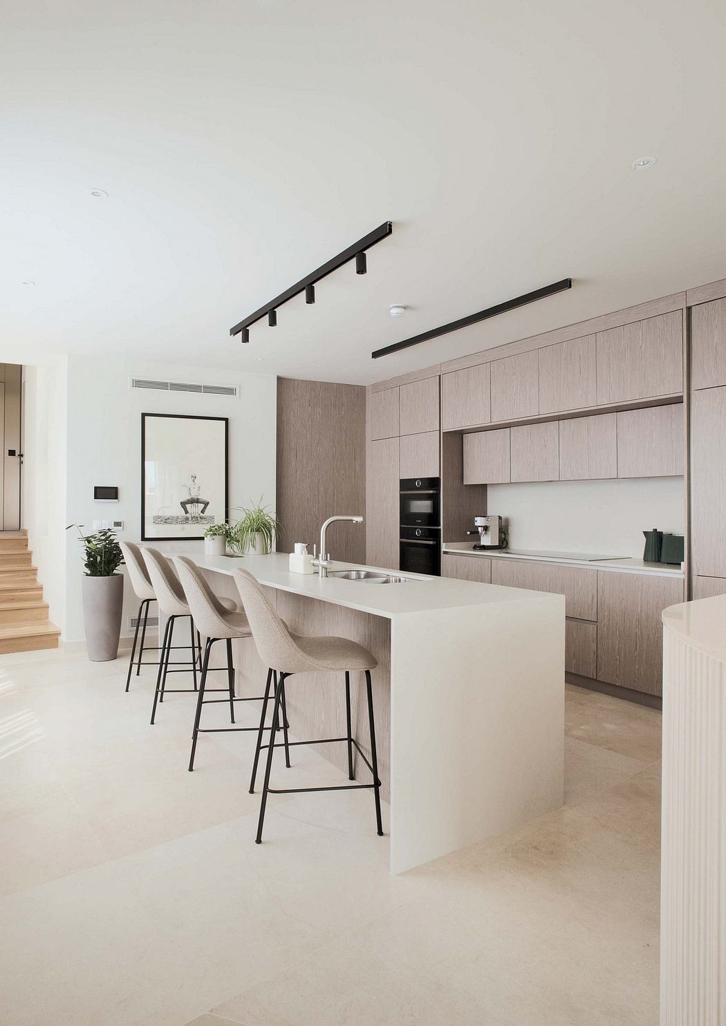 Modern kitchen with sleek cabinetry, minimalist lighting, and a central island with bar stools.