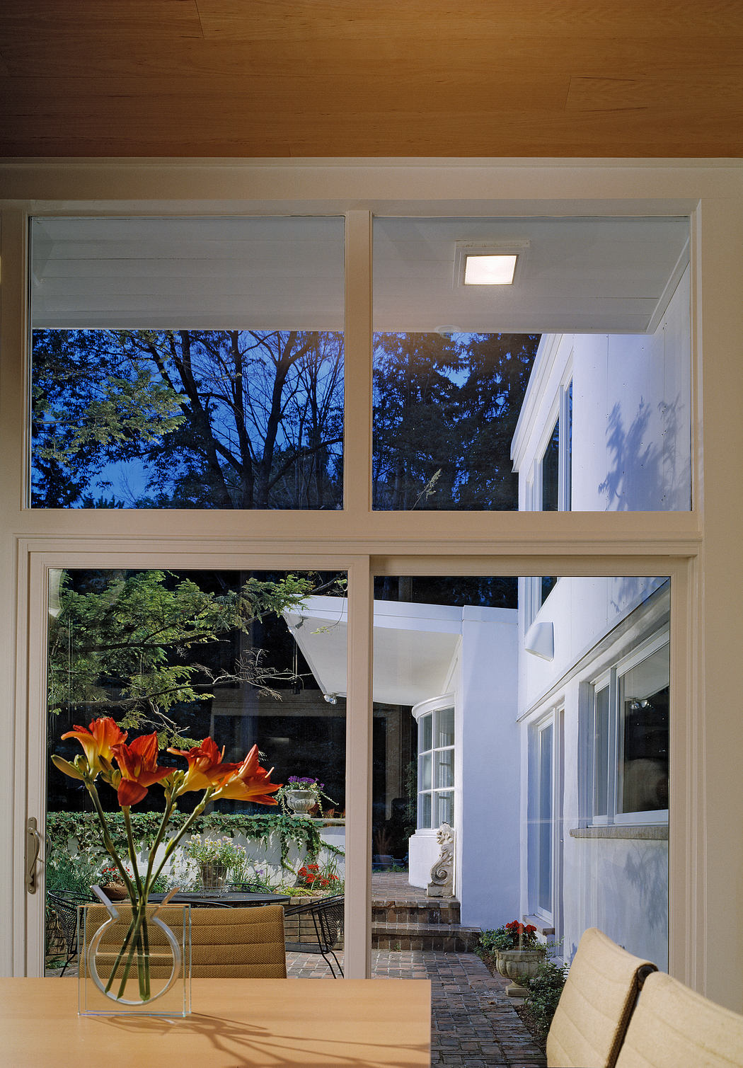 Warm interior with large windows overlooking a lush outdoor terrace and garden.