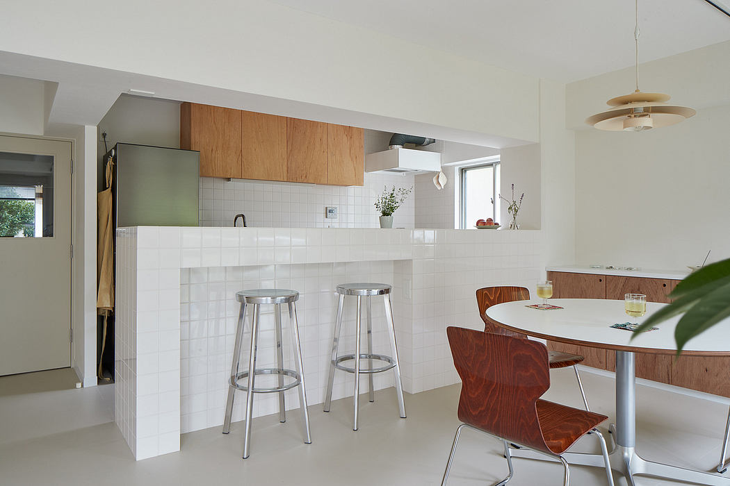 Modern kitchen with wooden cabinets, white tiles, and round dining table with chairs.