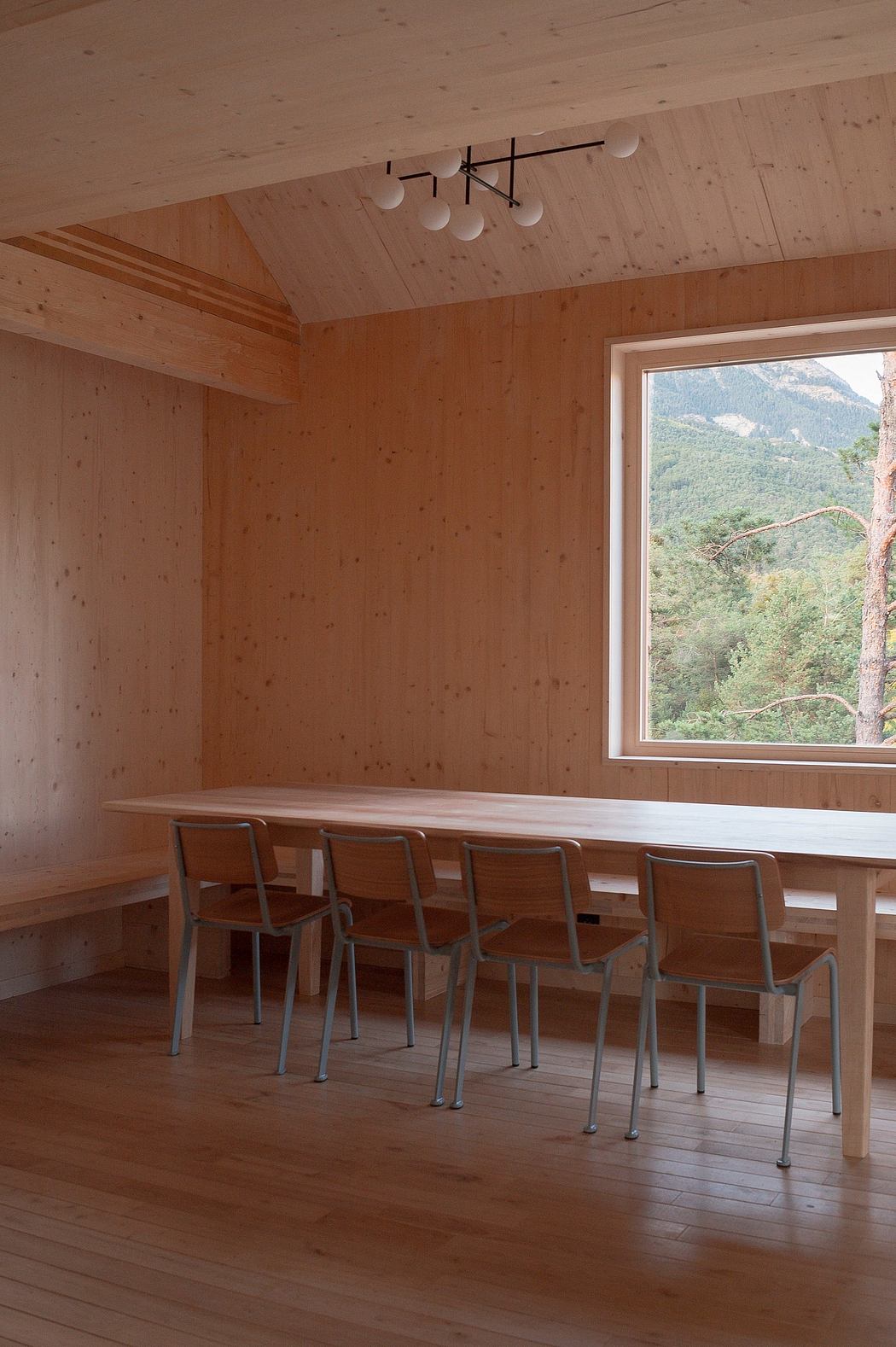 A modern wooden interior with a large window overlooking a forested landscape.