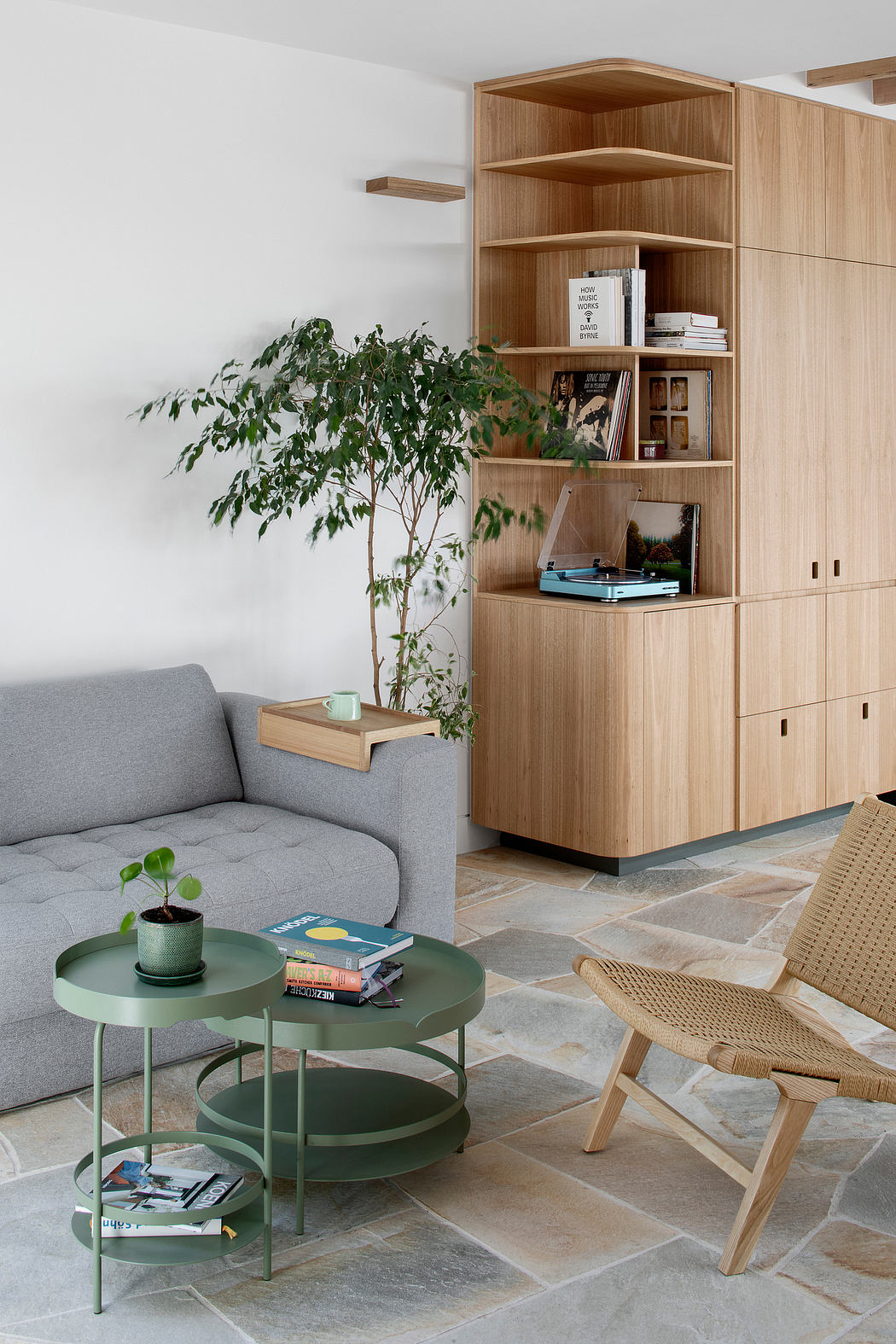 Cozy living room with wooden shelving unit, potted plant, and layered furniture.