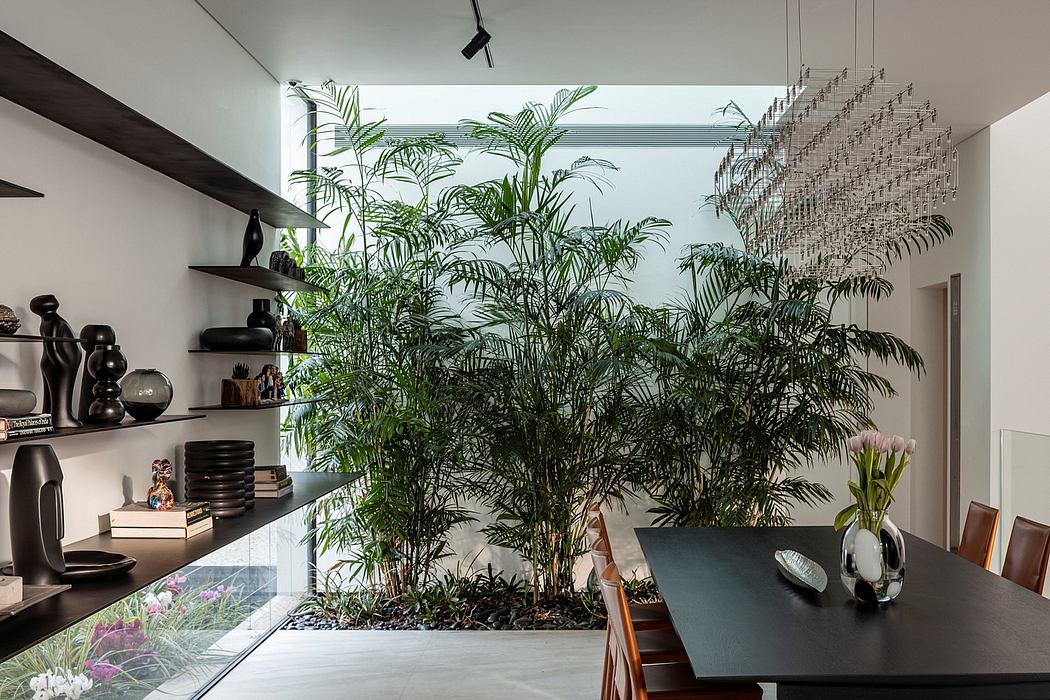 Lush tropical foliage, modern furniture, and a dramatic light fixture create an inviting space.