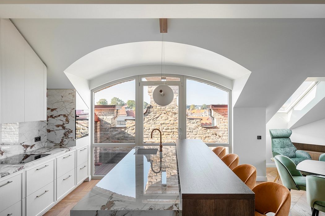 A modern kitchen with sleek white cabinets, stone countertops, and arched windows overlooking a brick exterior.