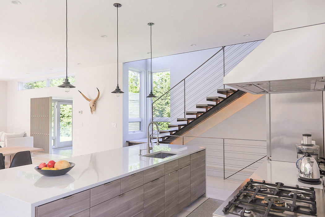 Modern kitchen with sleek cabinetry, stainless appliances, and a floating staircase.