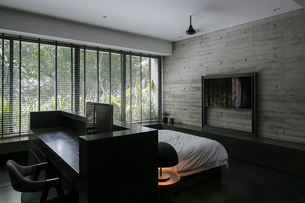 Minimalist bedroom design with concrete walls, large windows, and black furnishings.