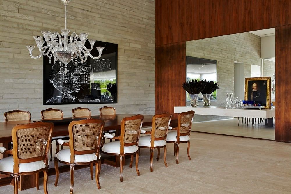 Elegant dining room with ornate chandelier, wooden furniture, and stone walls.