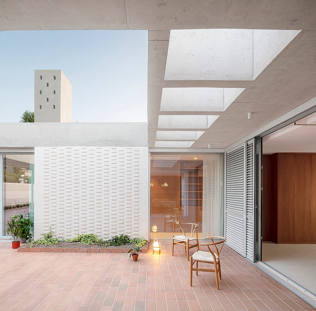 Modern concrete architecture with intricate brickwork patterns, open-concept interior, and cozy outdoor seating area.