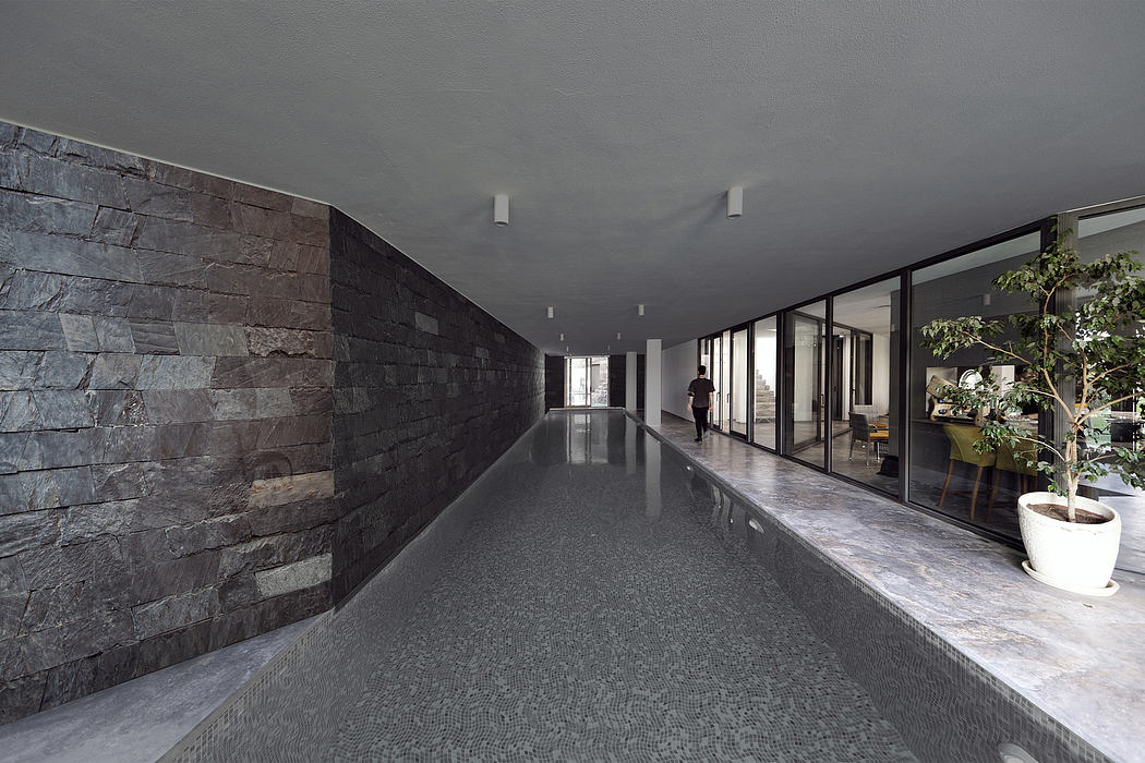 Sleek, minimalist interior with slate-gray stone walls, polished concrete floors, and large windows.