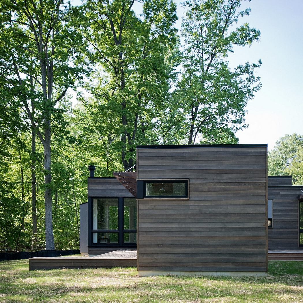 A modern, wood-clad structure with large windows set among lush green trees.