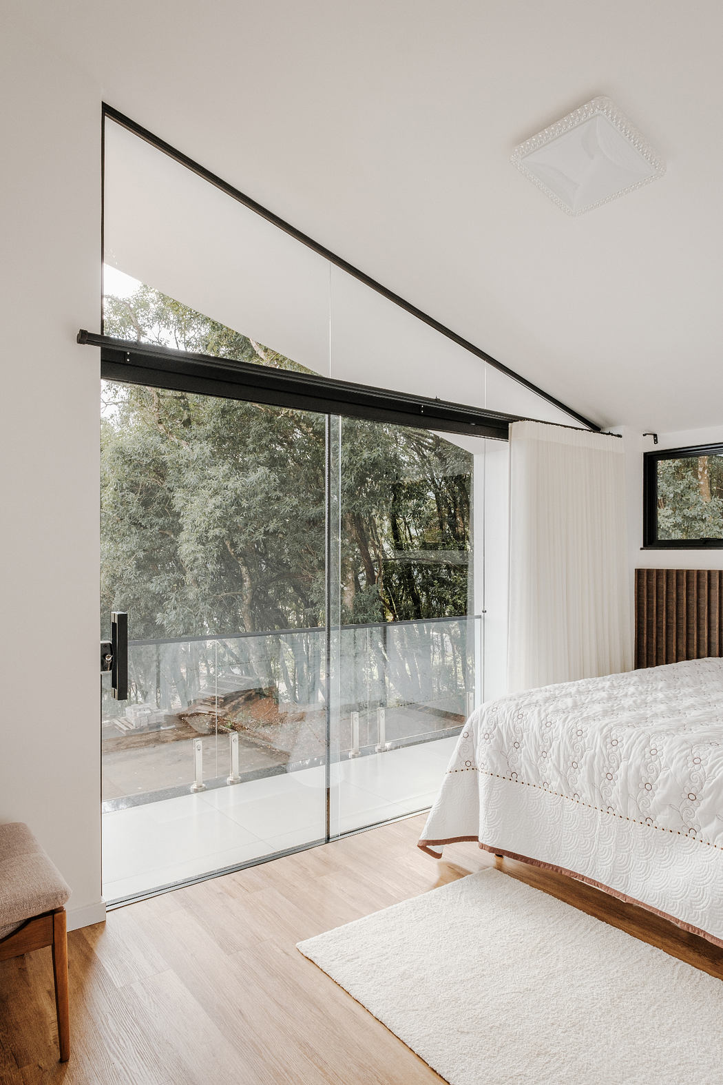 Spacious bedroom with large sliding glass doors overlooking lush treetops.