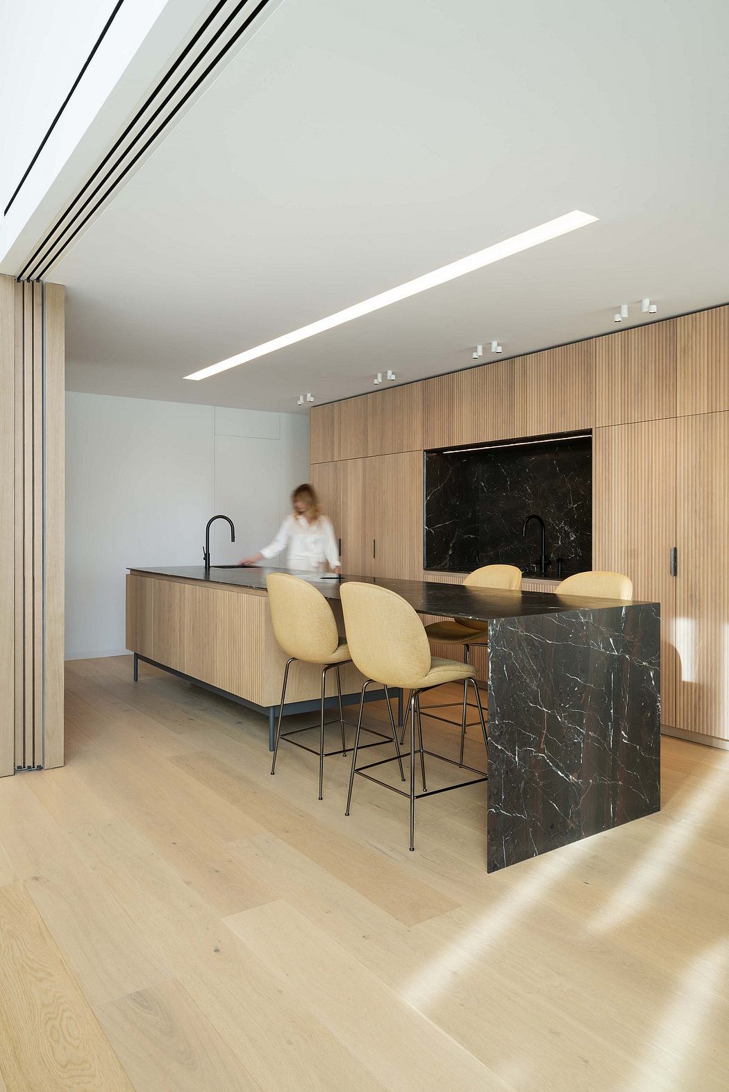 A sleek and modern kitchen with clean lines, wood paneling, and a striking marble island.