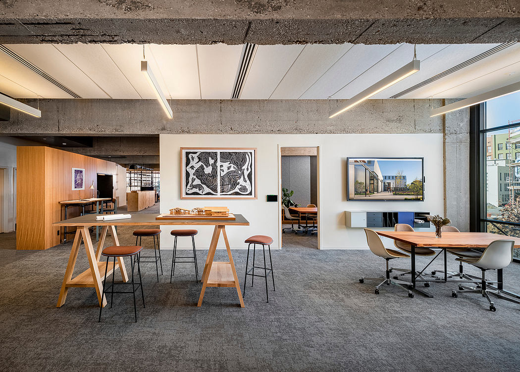 Modern, minimalist office space with concrete walls, wooden furnishings, and abstract artwork.