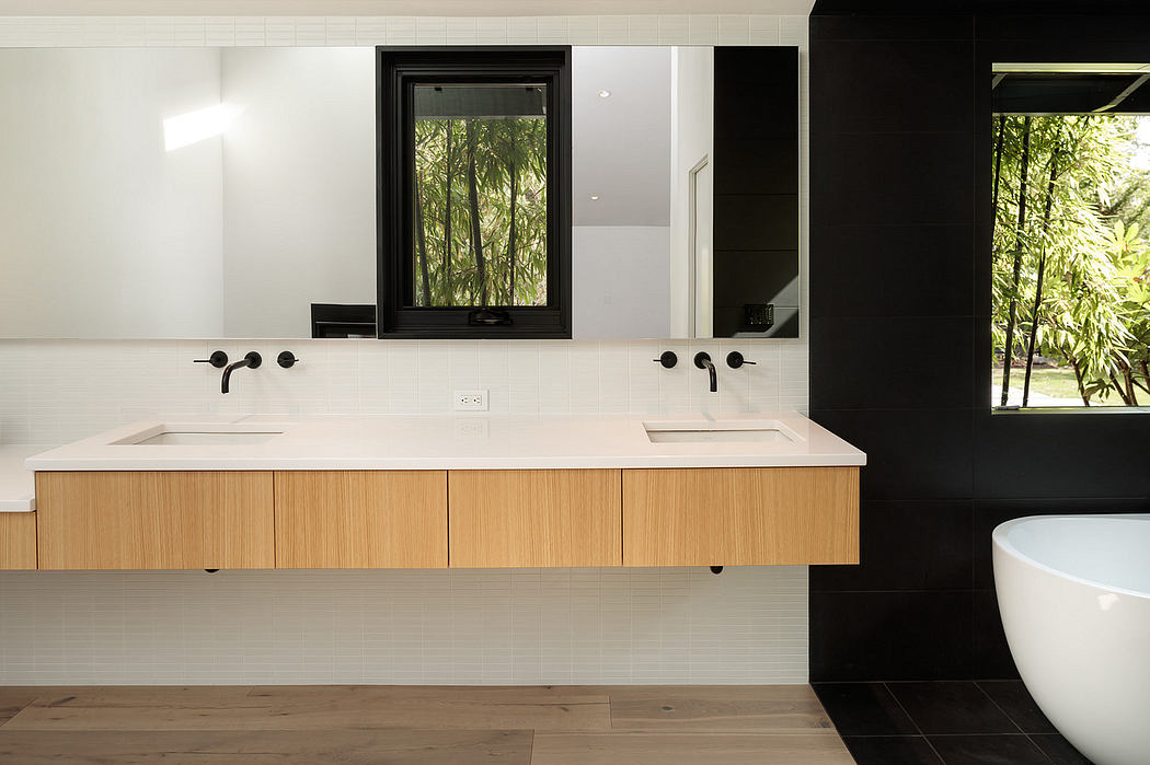 A modern bathroom with sleek white countertops, dark wood cabinets, and a large window overlooking lush greenery.