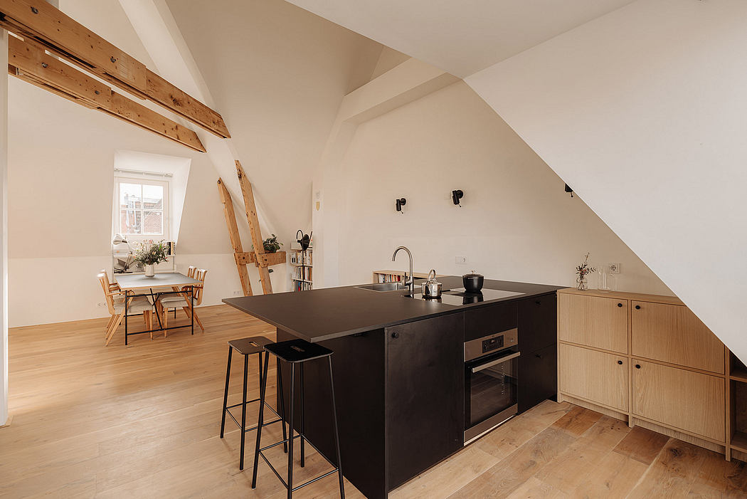 A modern kitchen with wooden beams, black island, and minimal furnishings in an airy space.