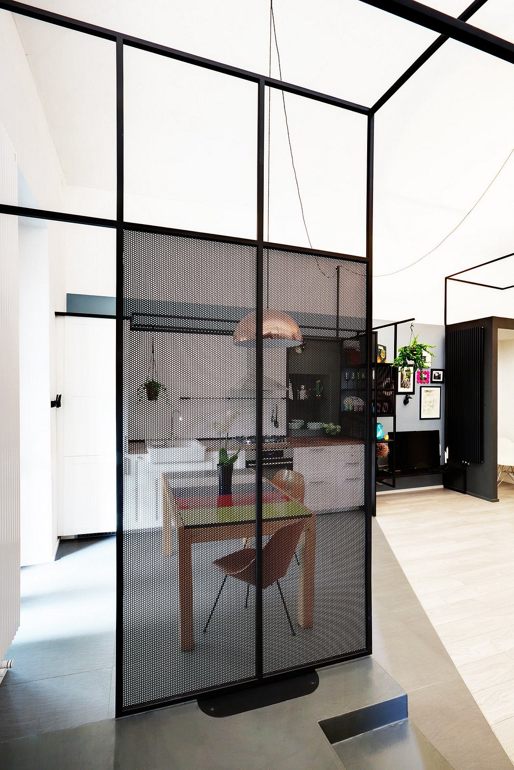 Black metal and glass partitions divide the open space, creating a modern and minimalist interior.