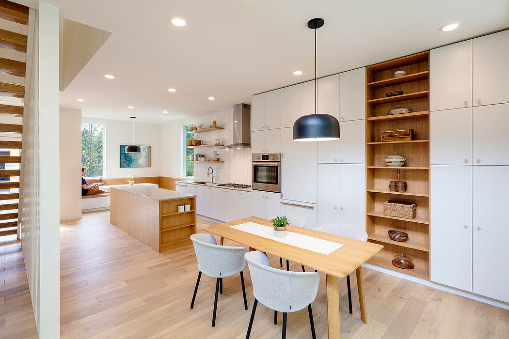 Bright, modern kitchen with white cabinets, wooden shelves, and a central dining table.