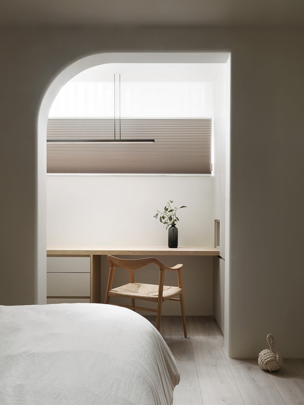 Minimalist bedroom with clean lines, wood furnishings, and a vase of greenery on the desk.