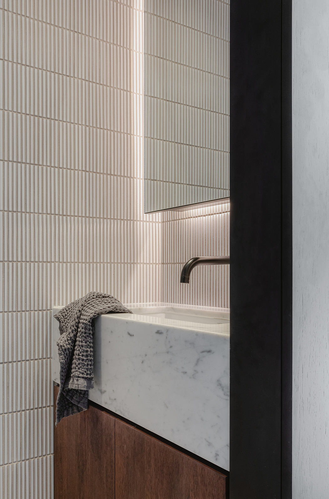 Modern bathroom with textured tile walls, marble vanity, and minimalist design.