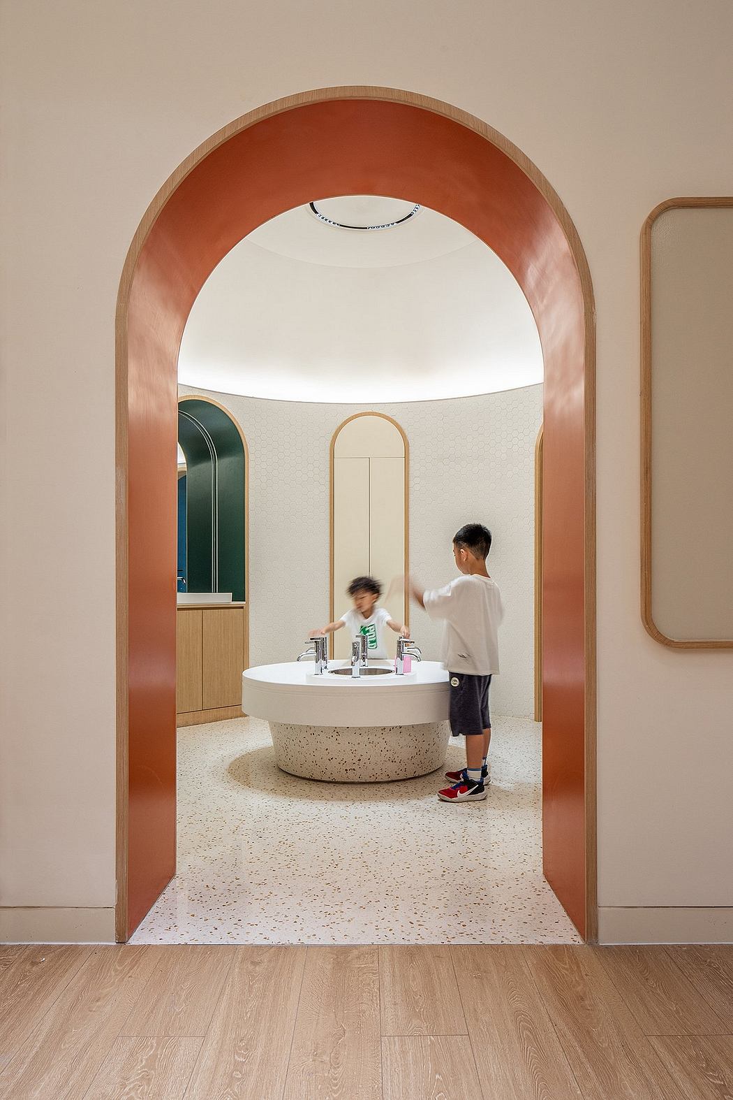 Curved archway frames a modern bathroom with a circular vanity and terrazzo flooring.