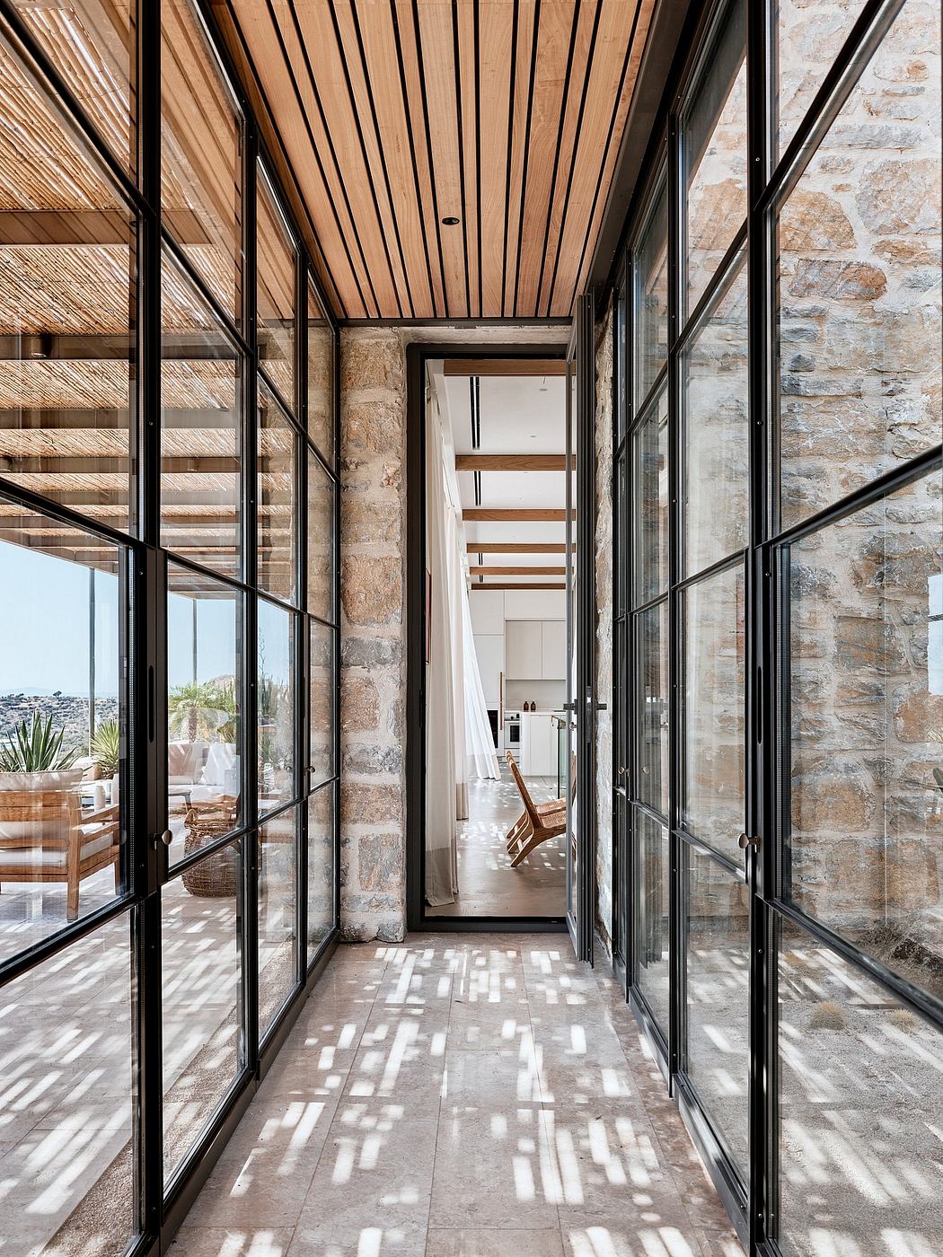 A modern, spacious interior with glass walls, stone accents, and a wooden ceiling.