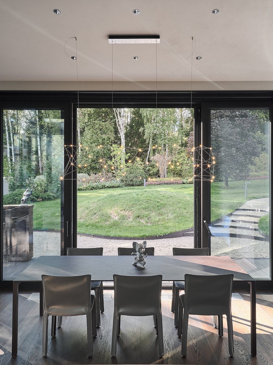 Modern dining room with floor-to-ceiling windows overlooking a lush, forested landscape.