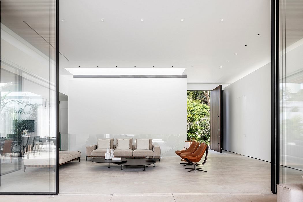Bright, modern living room with large windows, minimalist furniture, and lush greenery outside.