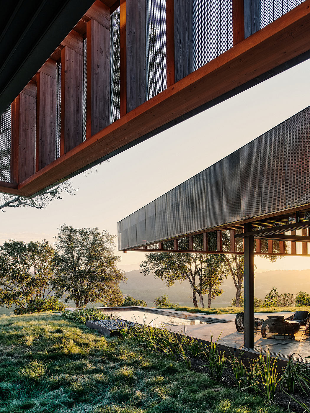 A modern, wooden structure with a large, cantilevered roof overlooking a serene landscape.